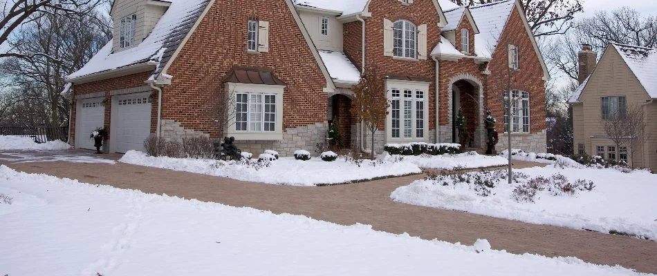 Snow around a cleared driveway of a brick house in Ann Arbor, MI.